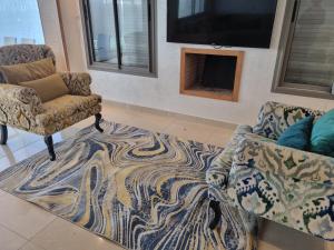 a living room with two chairs and a rug at Vill9 in Sidi Rahal