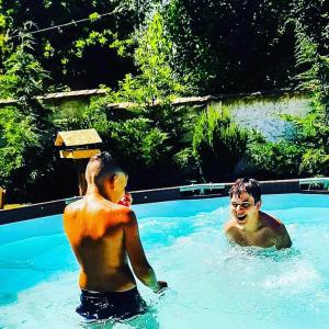 two men are swimming in a swimming pool at Rákóczi Guesthouse Miskolc in Miskolc