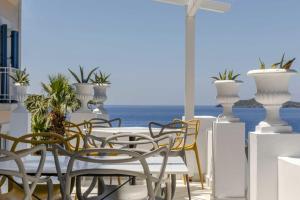 Aneroussa Beach Hotel في باتسي: طاولة وكراسي على شرفة مع المحيط