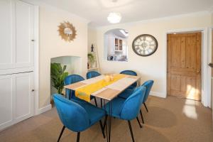 Un comedor con una mesa y sillas azules. en Cotswolds - 3 bed house, with Garden, WiFi - Esho Stays, en Cirencester