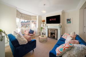 uma sala de estar com dois sofás azuis e uma lareira em Spacious home with garden Heart of the town WiFi Smart TV em Cirencester