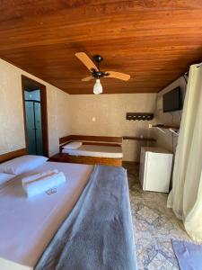 a bedroom with a bed with a ceiling fan at Bem Natural Pousada in Praia de Araçatiba