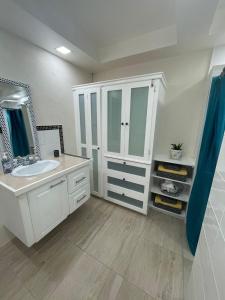 a white bathroom with a sink and a mirror at Scarlett Studios - Holiday-Business-US Embassy Appt 7 mins drive away - The one night only rate includes Airport and Embassy transportation in Bridgetown