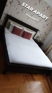 a bed with white sheets and red pillows in a room at Star Apart in Râmnicu Vâlcea