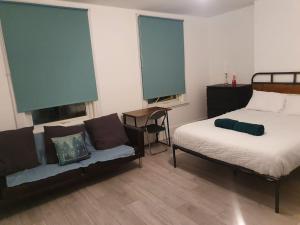 een slaapkamer met een bed, een bank en 2 ramen bij Spacious 5 bedroom House in South Norwood Croydon in Norwood