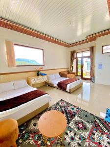 a bedroom with two beds and a large window at Madinna Villa Dieng in Dieng