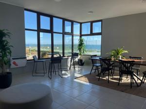 a dining room with tables and chairs and windows at Puerto Montt apartamento 1 en playa Pelluco in Puerto Montt