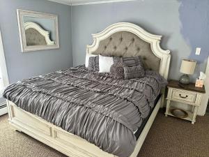 een slaapkamer met een groot bed met een grijs dekbed bij The Kelly House - 4 BR Historic Lodge - Downtown in Ellicottville