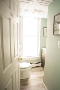 a bathroom with a toilet and a window at The Kelly House - 4 BR Historic Lodge - Downtown in Ellicottville