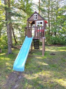 einen Spielplatz mit einer blauen Rutsche im Gras in der Unterkunft Rustic Pines Waterfront Cottage *CLEAR WATER* in Fenelon Falls