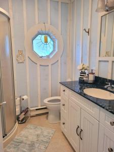 ein Bad mit einem Waschbecken, einem WC und einem Fenster in der Unterkunft Rustic Pines Waterfront Cottage *CLEAR WATER* in Fenelon Falls