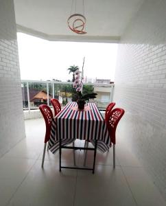 - une table à manger avec des chaises rouges et un vase dans l'établissement Excelente Apartamento no Centro de Bertioga, à Bertioga