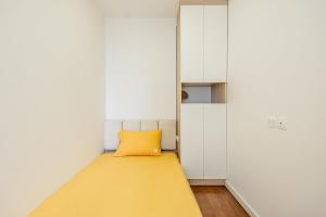een kleine kamer met een geel kussen op een bed bij Vinhomes D'Capitale 2-bed apartment with Sunset view in Hanoi