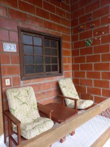 two chairs and a table in front of a brick wall at Martim de Sá - Caragua in Caraguatatuba