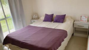 Un dormitorio con una cama con almohadas moradas y una ventana en Las Moras en San Luis