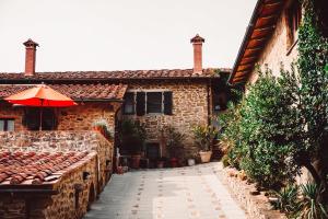 ein Steinhaus mit einem roten Regenschirm davor in der Unterkunft Podere L'Aquila in Gaiole in Chianti