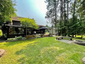 een tuin met twee banken en een huis bij Whispering Pines Riverside Retreat in Coboconk
