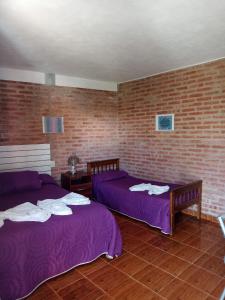 Habitación con 2 camas y pared de ladrillo en Complejo Navi en Mina Clavero