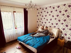 dwoje osób siedzących na łóżku w sypialni w obiekcie Villa Lake&Forest Trójmiasto w mieście Dobrzewino
