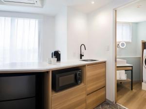 a kitchen with a sink and a microwave on a counter at Tokyu Stay Shibuya Shin-Minamiguchi in Tokyo