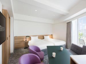 une chambre d'hôtel avec un lit et des chaises violettes dans l'établissement Tokyu Stay Shibuya Shin-Minamiguchi, à Tokyo
