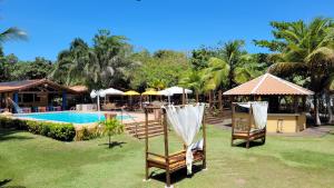 a resort with a pool and two chairs and umbrellas at Pousada Beach Bahia in Porto Seguro