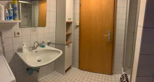 ein Badezimmer mit einem Waschbecken und einer Holztür in der Unterkunft Ferienwohnung Hofer in Altötting