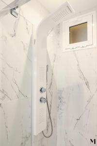 a shower in a white bathroom with marble walls at Aqua Vista Playa San Juan in Playa de San Juan