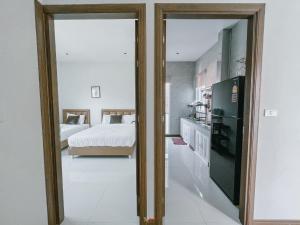 a kitchen with a refrigerator and a bedroom with a bed at Nayjoe Poolvilla Cha-am in Cha Am