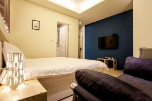 a bedroom with a bed and a couch and a tv at Biau Tsan Su in Taichung