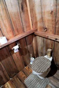 a wooden bathroom with a toilet and a roll of toilet paper at Natty Tropical Valley in Roseau
