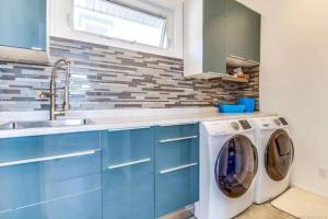 eine blaue Küche mit einer Waschmaschine und einem Waschbecken in der Unterkunft The Infiniti Villa in Kelowna