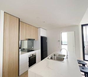 a kitchen with a sink and a black refrigerator at Chermside deluxe 3 bedroom brand new apartment in Brisbane