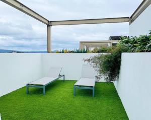 2 chaises blanches assises au-dessus d'une pelouse verte dans l'établissement Chermside deluxe 3 bedroom brand new apartment, à Brisbane