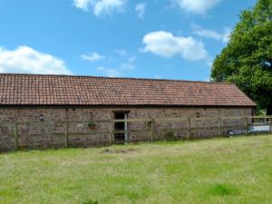an old brick barn with a grass field in front of it at Court Park Barn in Tidenham