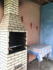 a brick oven with a table in a room at Nossa Chácara na Praia 3suits,Camp,Pisci,Churrasqueira e estacionamento in Arraial do Cabo