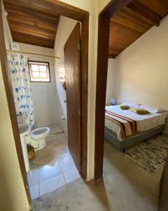 a bedroom with a bed and a bathroom with a toilet at Suítes Canto do Nema in Ilhabela