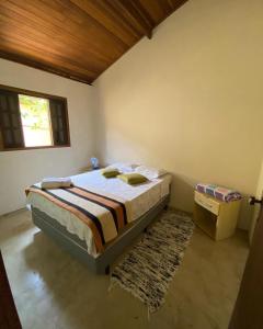 a bedroom with a bed and a window and a rug at Suítes Canto do Nema in Ilhabela