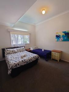 een slaapkamer met een bed, een tafel en een raam bij Top of the Lake Holiday Units in Merimbula