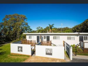 a white house with a fence and a yard at Top of the Lake Holiday Units in Merimbula