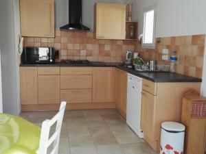a small kitchen with wooden cabinets and a table at Villa Moderne et Calme, Proche Plage, Centre-Ville, 6 Pers., Jardin, Tout Confort - FR-1-476-87 in La Faute-sur-Mer