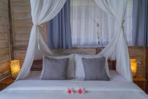 sypialnia z białym łóżkiem z 2 różowymi kwiatami w obiekcie Ananda JJ Ubud Resort & Spa w mieście Ubud
