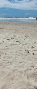 a beach with footprints in the sand and the ocean at Apto com Varanda 104 - Balneário Arroio do Silva - 300 metros do Mar in Arroio do Silva