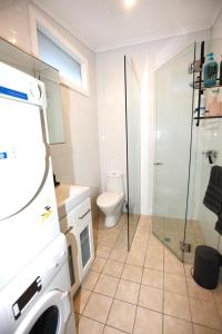 a bathroom with a toilet and a washing machine at The Pavilion End - Central Paddington Apartment in Sydney