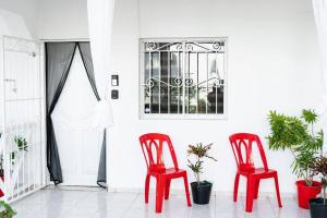 蓬塔卡納的住宿－Hermosa Suites #2 in the heart of PUNTA CANA，两把红色椅子,有植物的房间