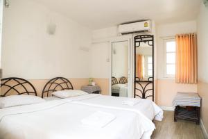 a white bedroom with two beds and a mirror at White Lodge Hotel Bangkok in Bangkok