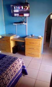 a bedroom with a bed and a desk and a tv at Finch Apartment in Gwa Kay