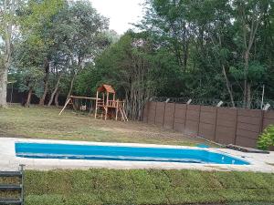 patio trasero con mesa de madera y parque infantil en Quinta Luna Morada en General Rodríguez