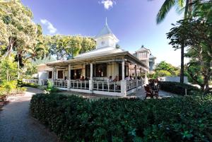a white house with people sitting on a porch at Sandpipers Beach House in Palm Cove