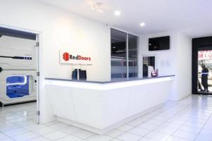 a restaurant with a white counter with a red rover sign at RedDoorz Hostel near Taman Puring in Jakarta